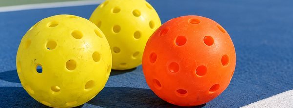 Yellow and orange pickleballs on a court
