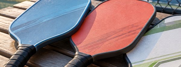 Blue, coral and white pickleball paddles on a bench