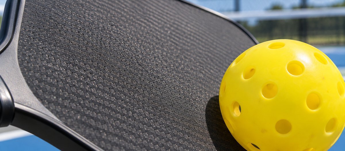 Close view of a textured carbon paddle face with a pickleball