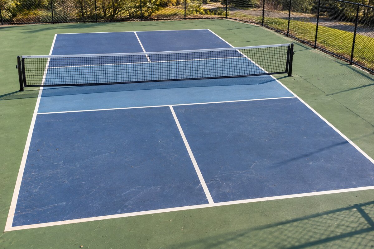 An outdoor pickleball court showing the full court lines and non-volley zone from a slightly elevated angle