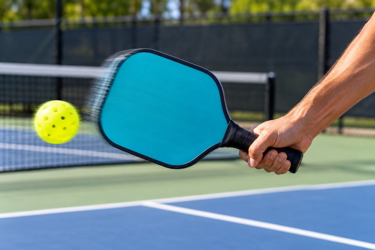 Pickleball paddle mid swing hitting the ball, a usa pickleball approved paddle that still has to fit the player